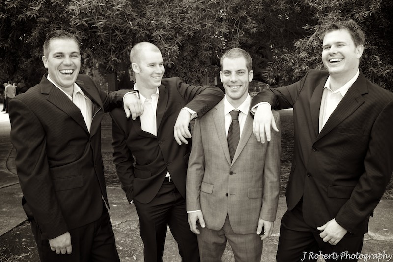 Sepia groom laughing with groomsmen - wedding photography sydney